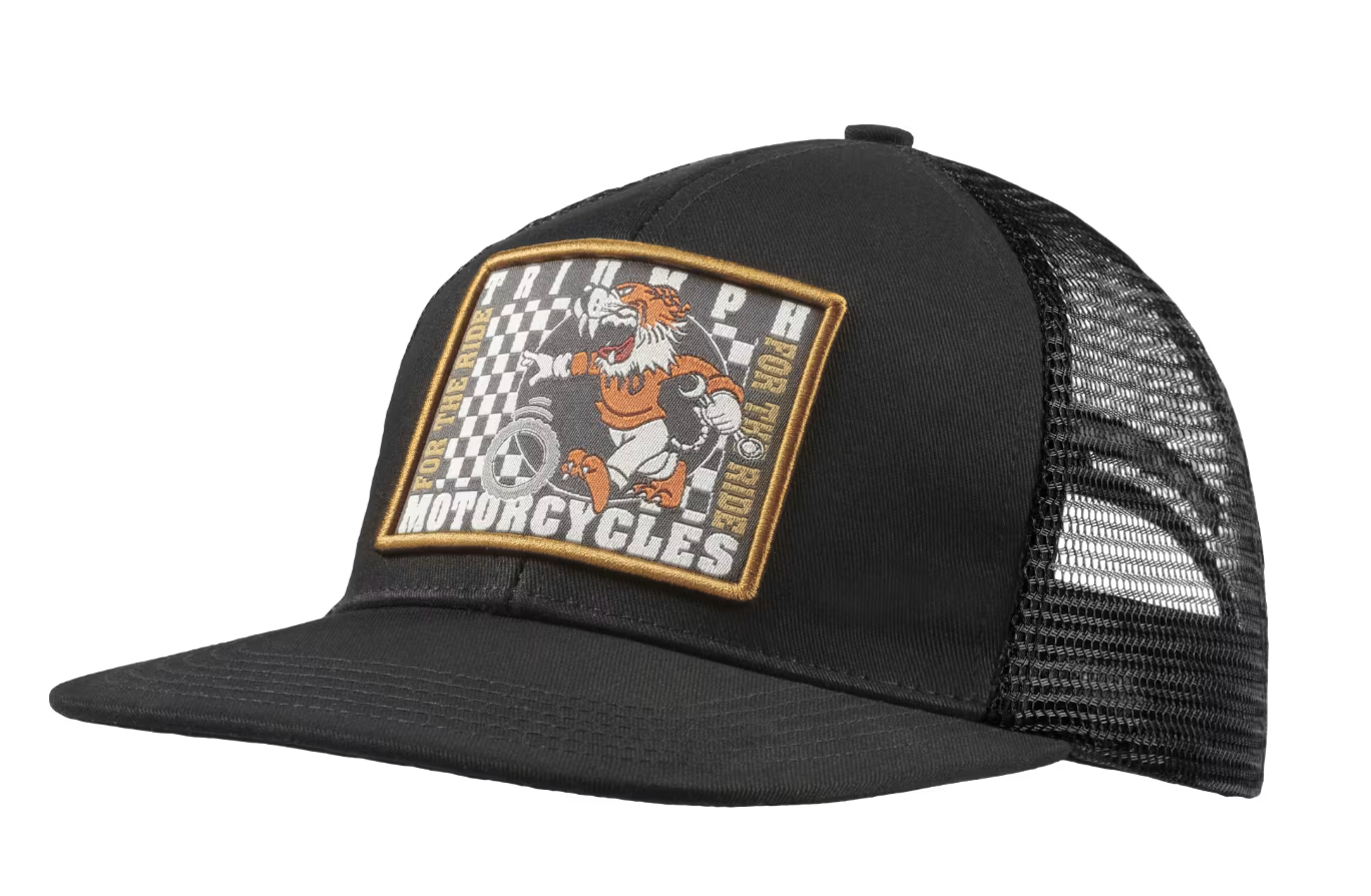 A black trucker hat with a curved brim and black mesh back panels, featuring a rectangular front patch with a tiger graphic and the text 'TRIUMPH MOTORCYCLES 2024' on a white background.